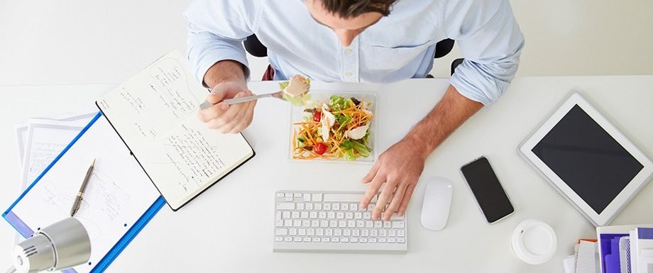 Hombre comiendo comida saludable en la oficina